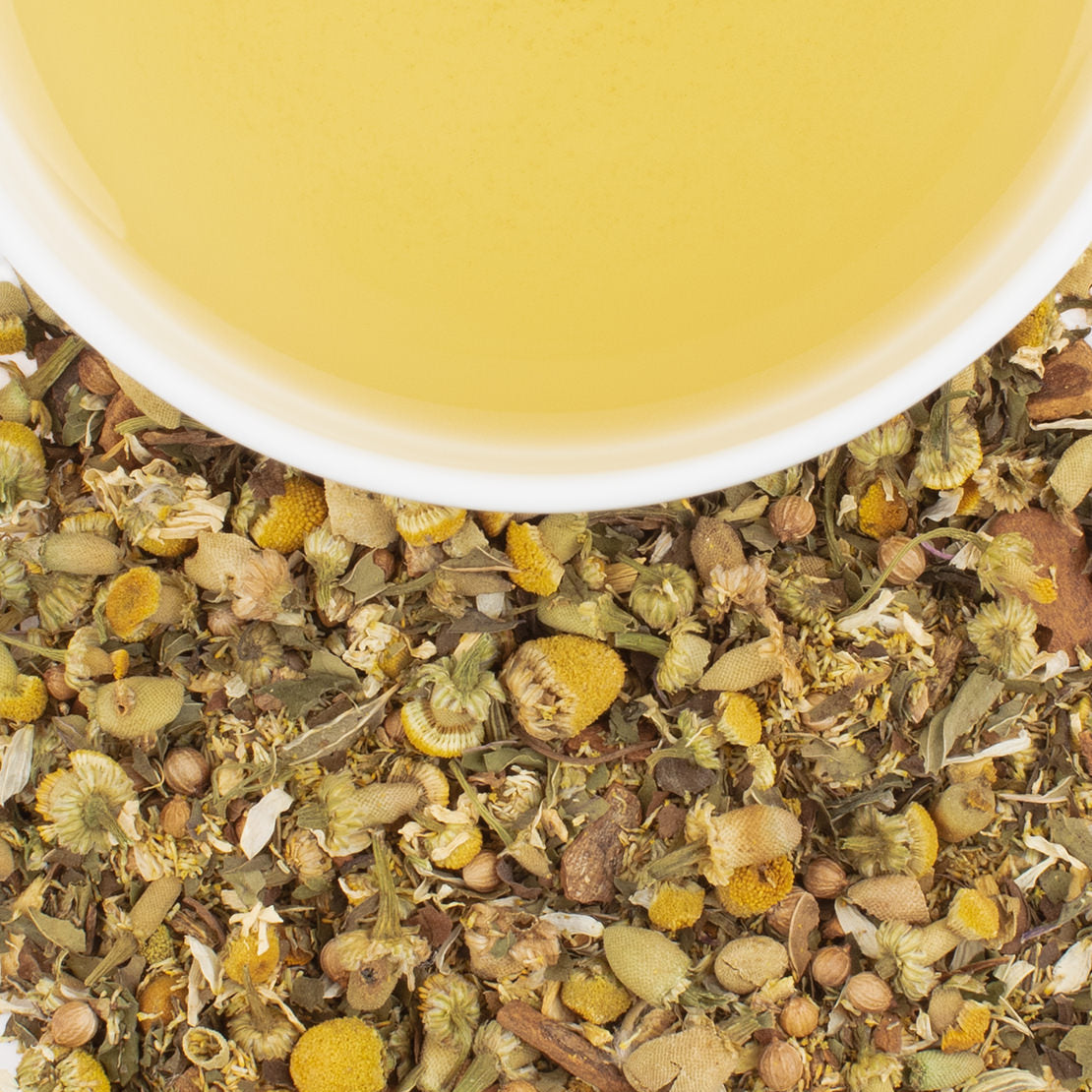 Herbal tea leaves with a cup of tea in the background
