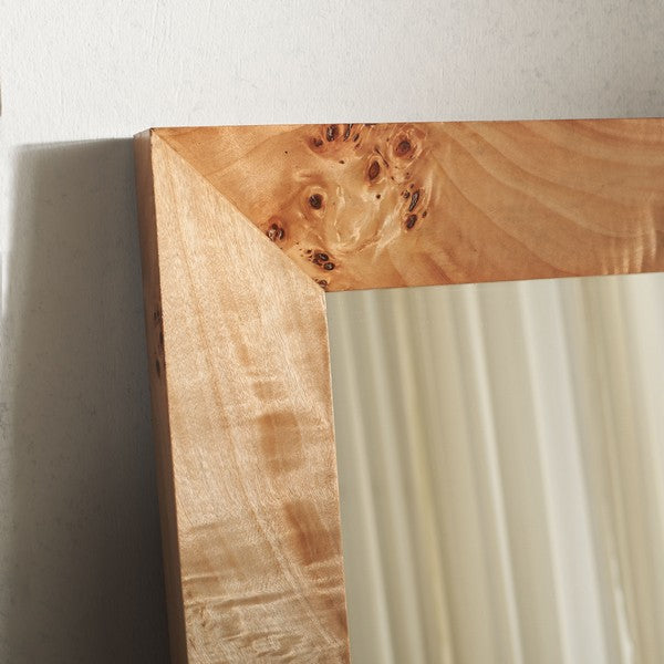 Wooden mirror frame with natural grain and texture on a white wall.