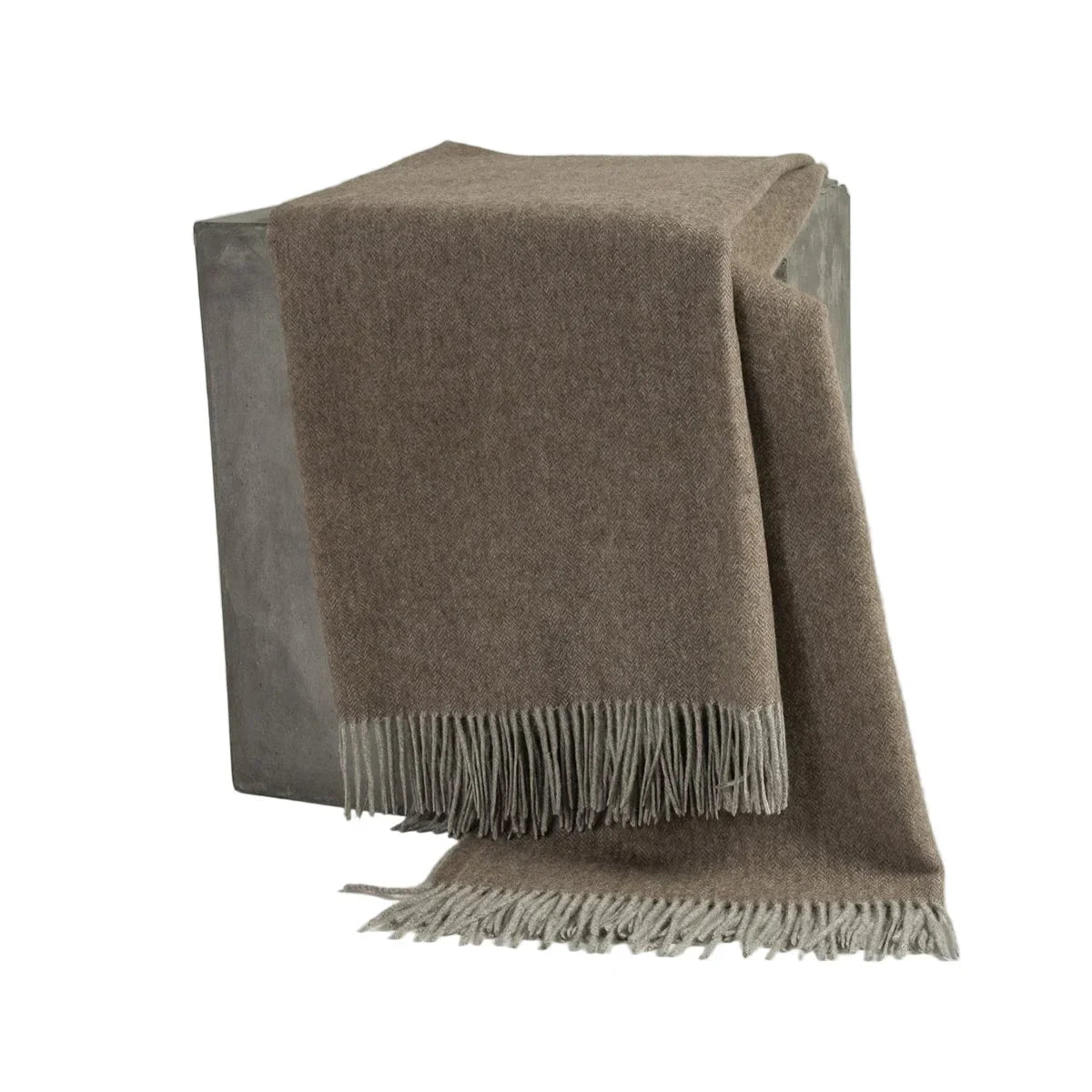 Brown blanket with fringes draped over a wooden stool on a white background