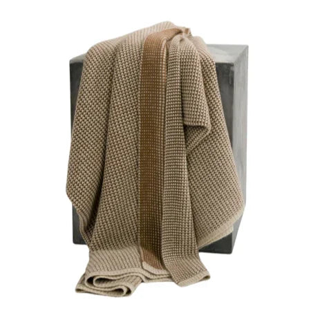 Beige knitted blanket draped over a chair on a white background