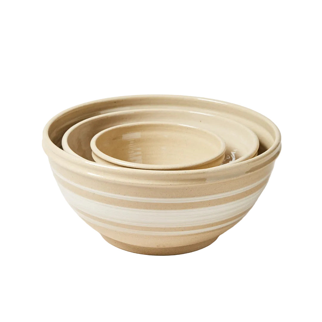 Set of three beige ceramic bowls on a light background